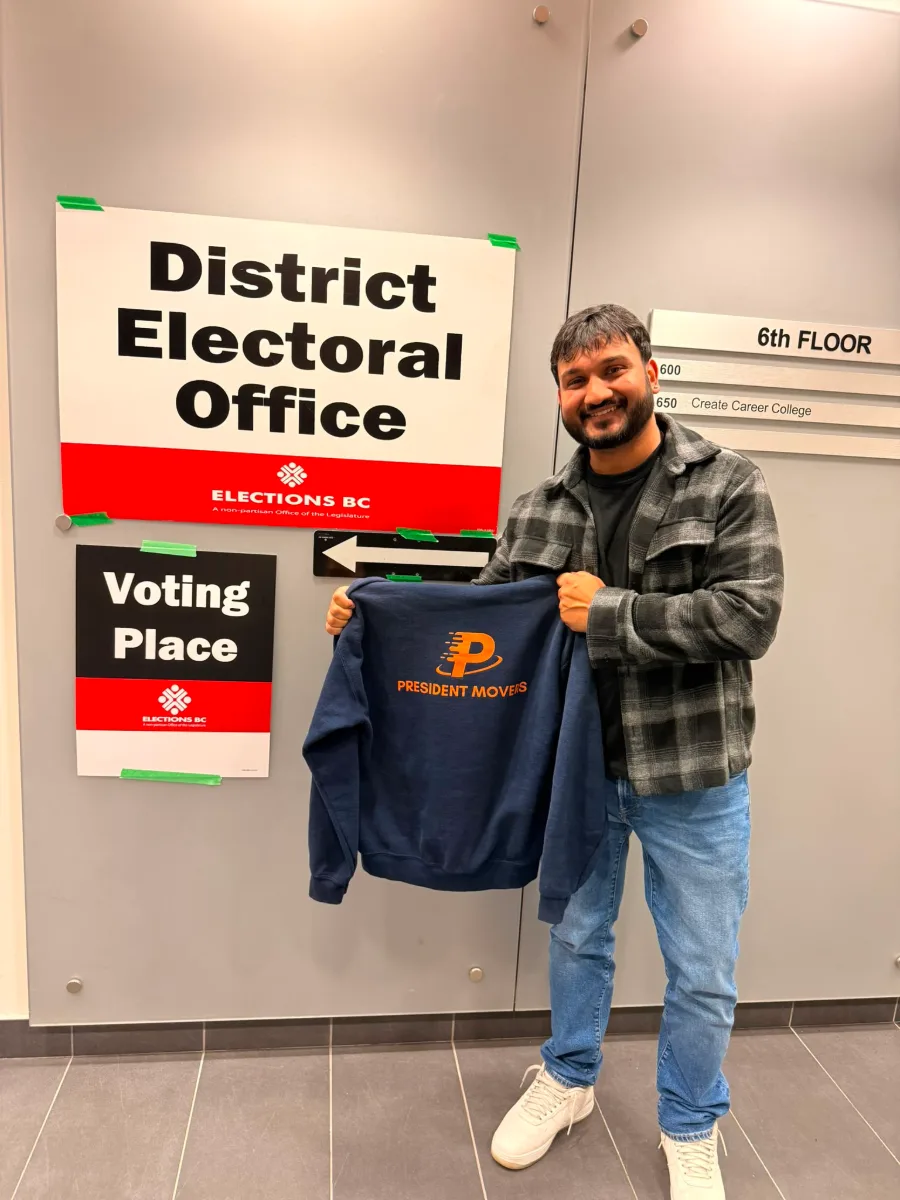 President Movers team member holding a President Movers sweater outside the Elections BC District Electoral Office in Burnaby